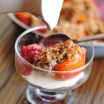 glass dish gluten-free peach crumble with cream being poured on top
