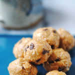 she made gluten-free oatmeal peanut butter chocolate chip energy bites rolled into balls and stacked on top of each other on a blue plate