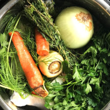 instant pot full of bone broth ingredients with carrot and onion on top