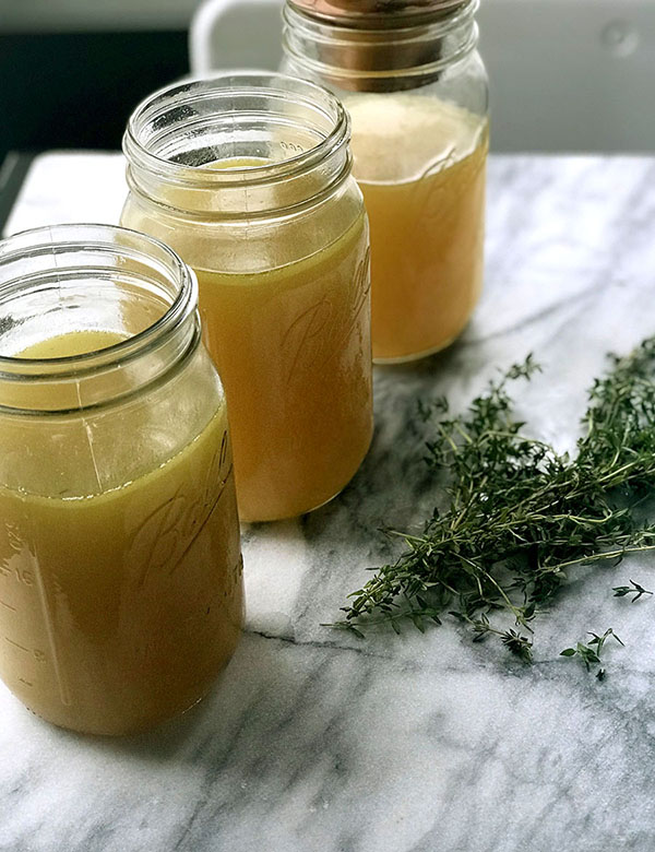 instant pot chicken bone broth in mason jars on counter with fresh thyme 