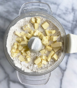 food processor bowl with scone flour mixture and cubed butter on top