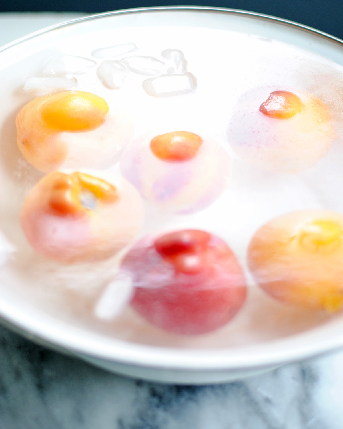 whole peaches floating in an bowl of water with ice