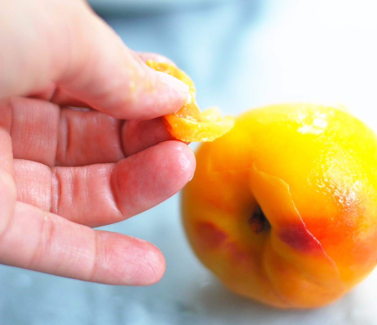 peeling the skin off a peach with hands