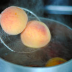 two peaches being dropped into boiling water