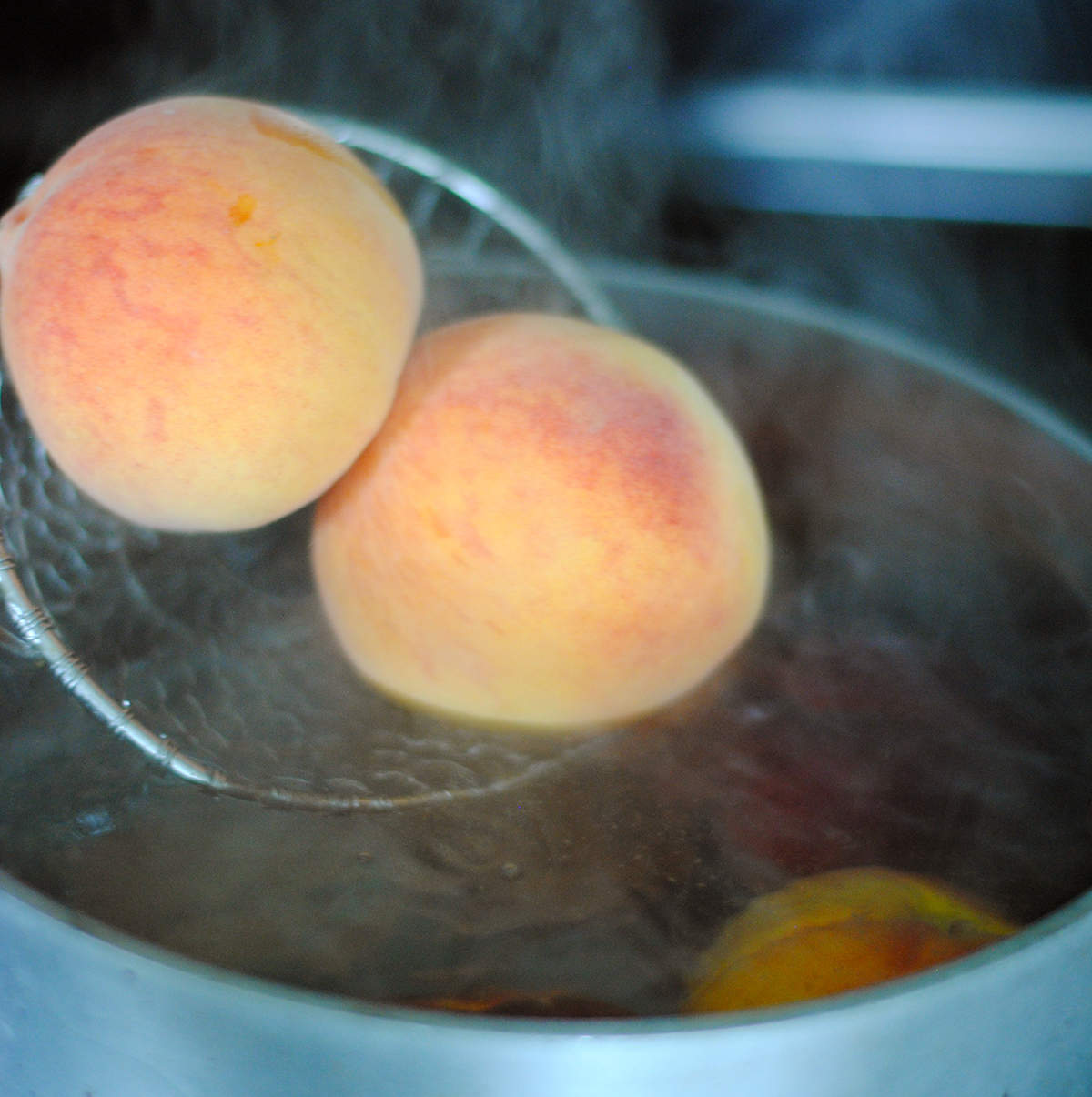 two peaches being dropped into boiling water 