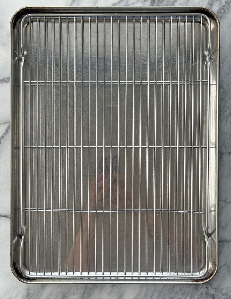 Mirrored baking sheet with cooling rack sitting inside it sitting on marble counter. 
