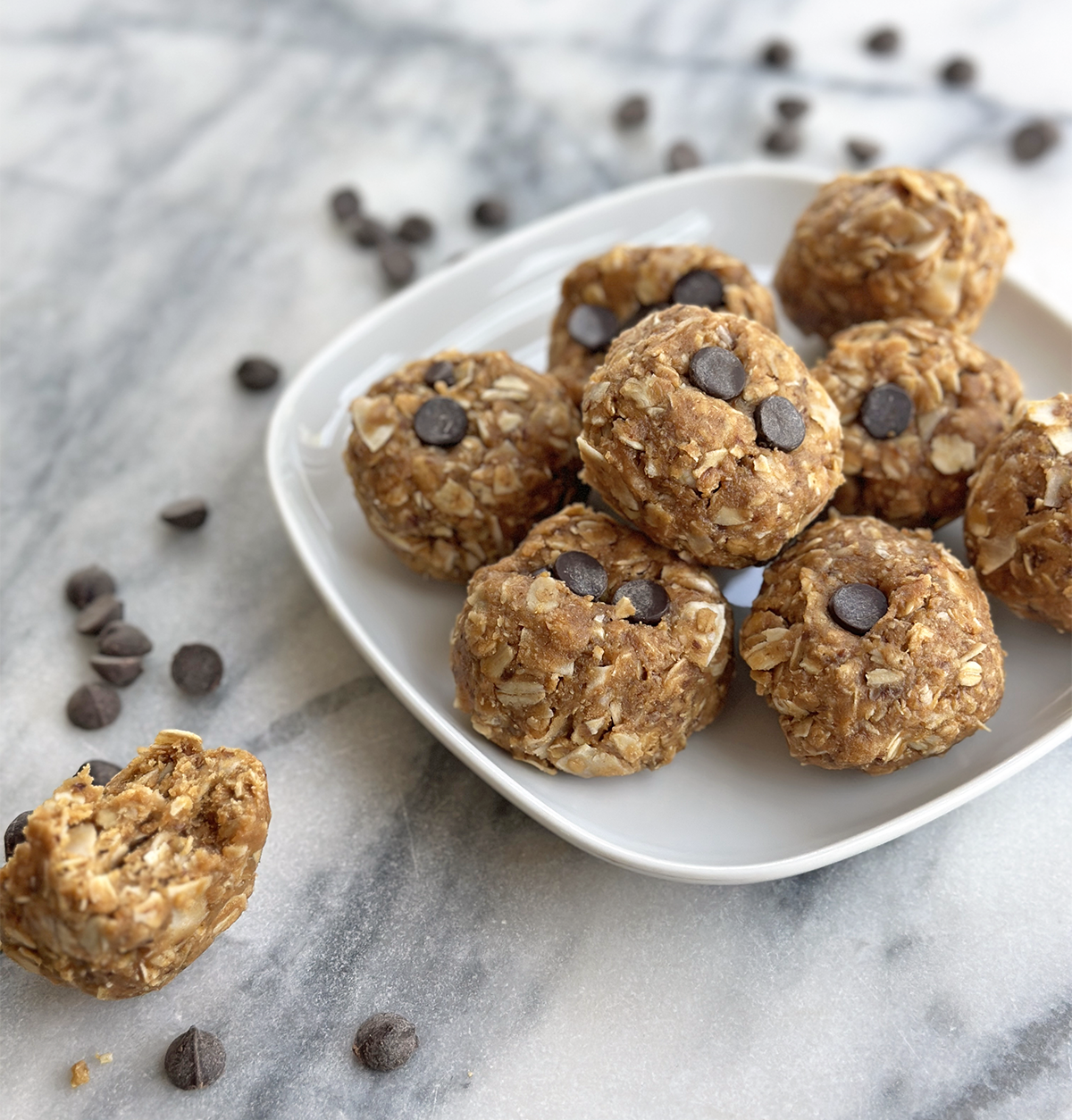 Plate of oat and nut butter energy bites with chocolate chips on top – no-bake protein snack recipe made with oats, nut butter, and honey.