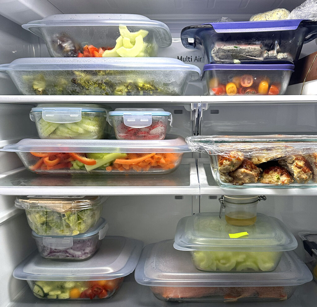 inside of a fridge with meal prepped meals in glassware with blue lids