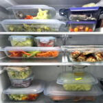 inside of a fridge with meal prepped meals in glassware with blue lids