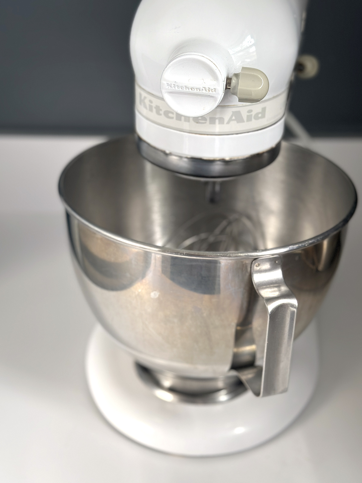 kitchen aid mixer with white base and silver bowl sitting on white counter