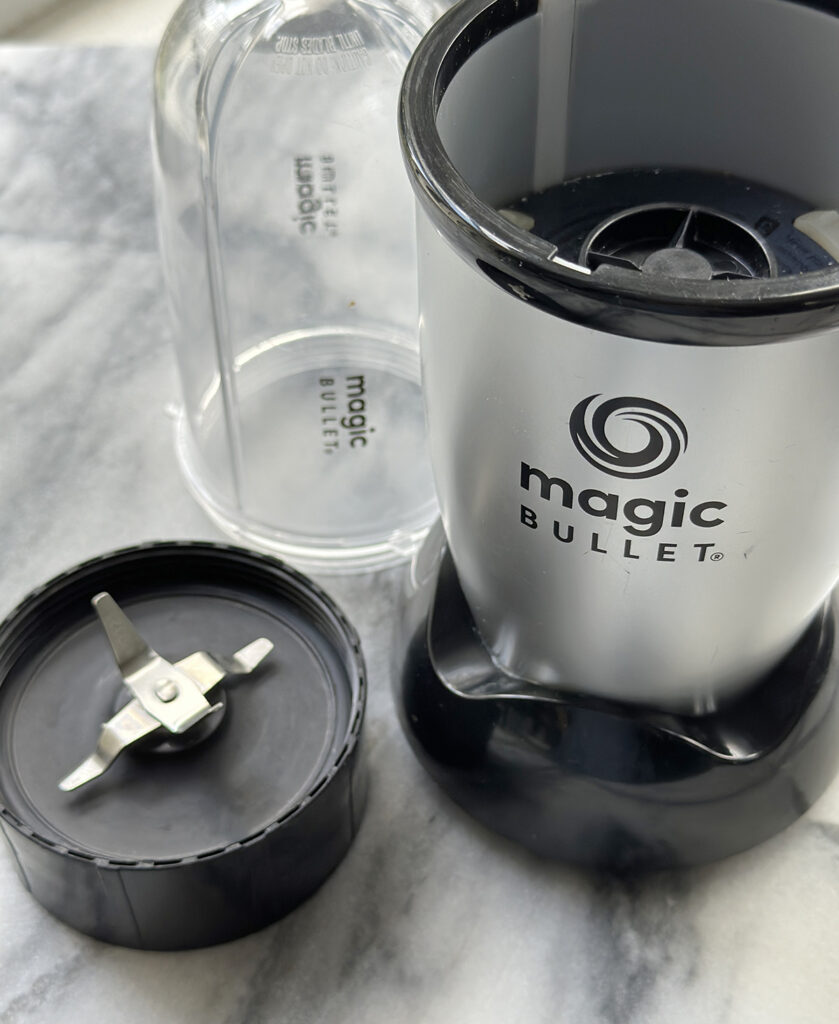 magic bullet mini blender base with blade and cup sitting on marble surface