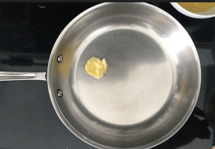Ghee melting in a stainless steel pan before adding eggs