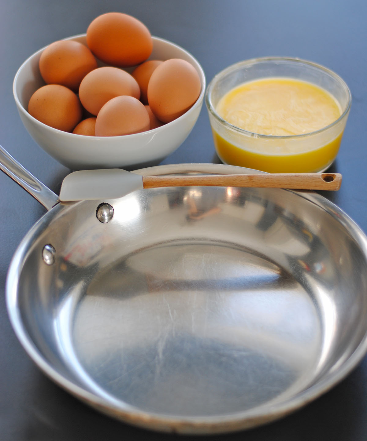Stainless steel pan with spatula, eggs, and salt on a counter

