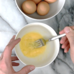 Whisking eggs on a marble surface for scrambled eggs
