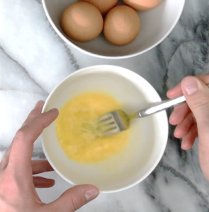Whisking eggs on a marble surface for scrambled eggs