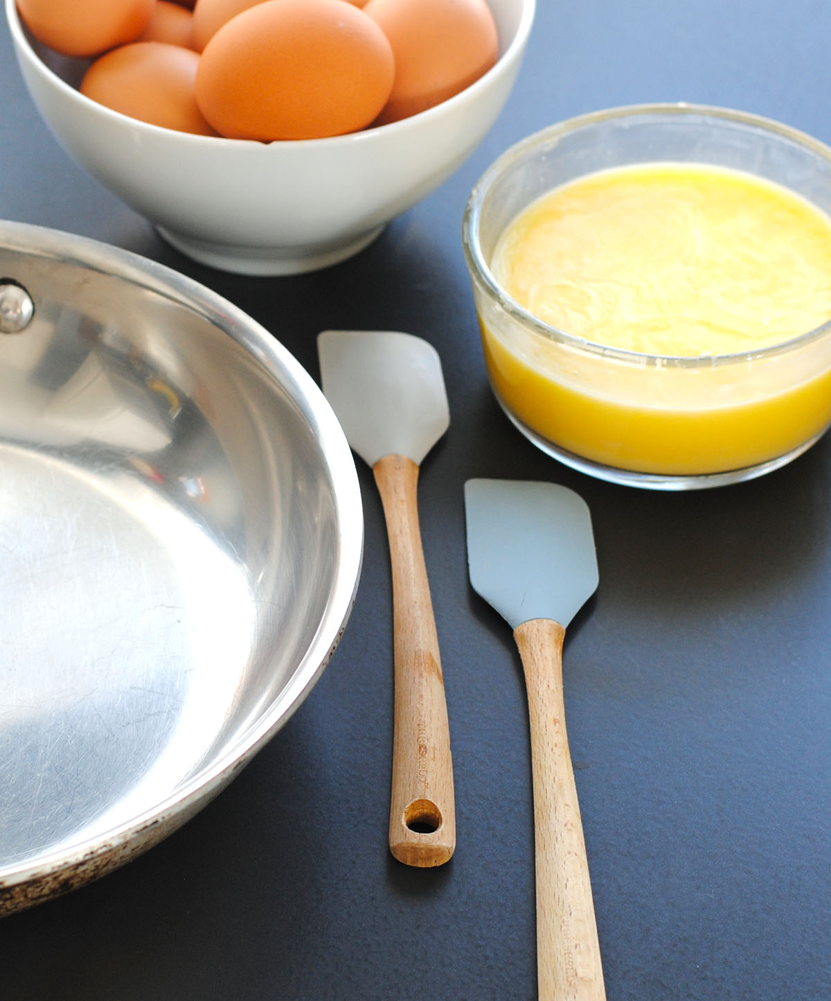 Close-up of two silicone spatulas for scrambling eggs in a stainless steel pan


