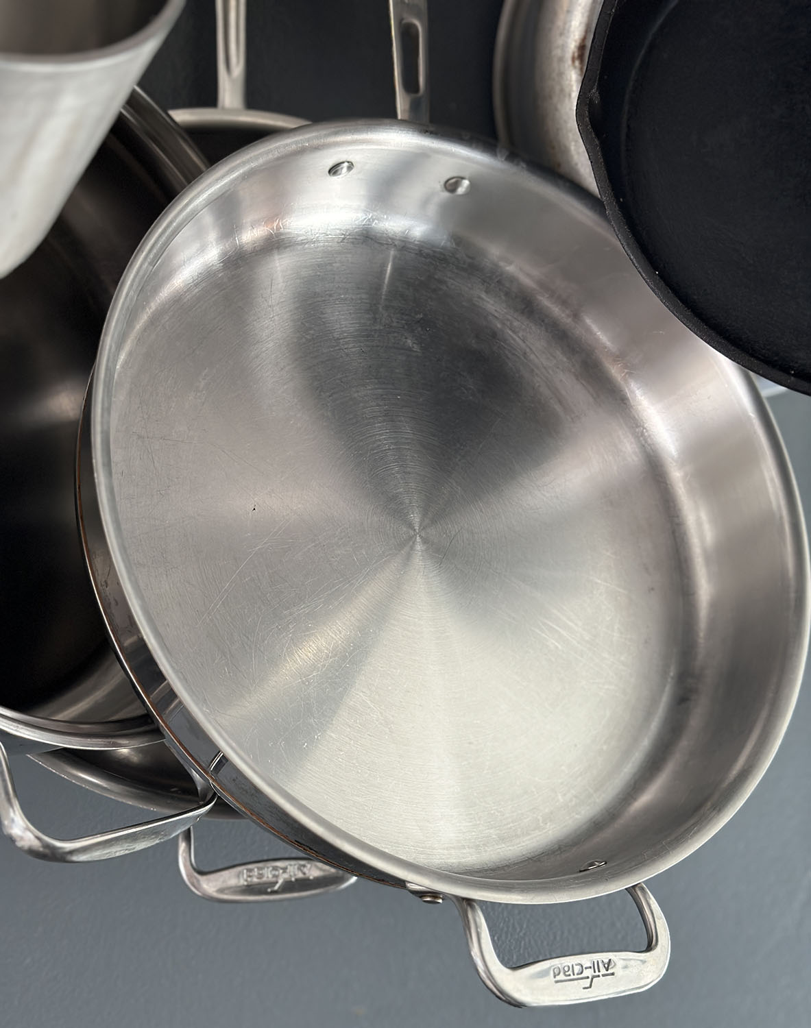 large stainless steel skillet hanging on a pot rack