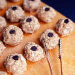 Batch of oat and nut butter energy bites topped with chocolate chips on a cutting board – protein snack recipe for meal prep.