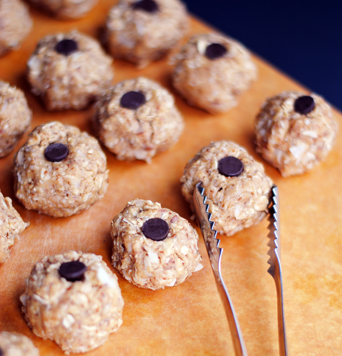 Batch of oat and nut butter energy bites topped with chocolate chips on a cutting board – protein snack recipe for meal prep.