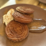 Gluten-free churros with cinnamon whipped cream and dulce sauce on a brown plate at Colita, a 100% gluten-free restaurant in Minneapolis