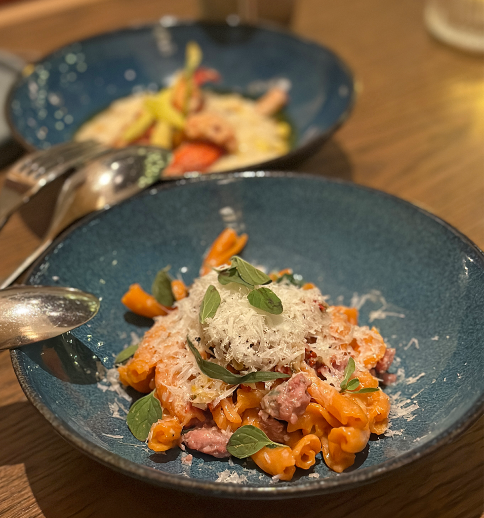 Blue bowl of gluten-free pasta with sauce and herbs at Mara restaurant in Minneapolis.