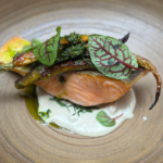 Close-up of seared salmon with crispy skin topped with greens and vegetables at Spoon and Stable in Minneapolis.