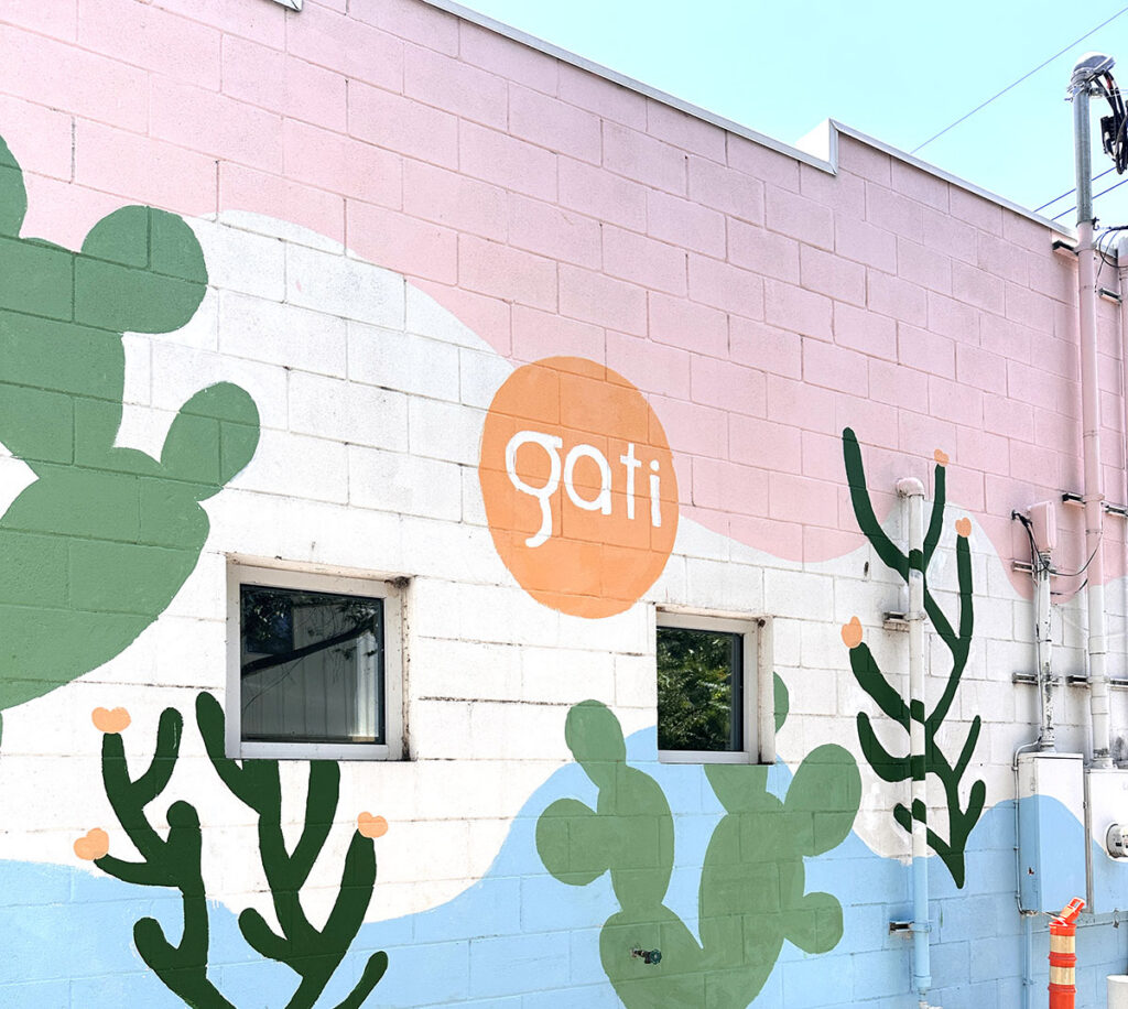 Colorful cactus mural with the Gati logo on the wall of Gati Cafe, a gluten-free ice cream shop in Austin